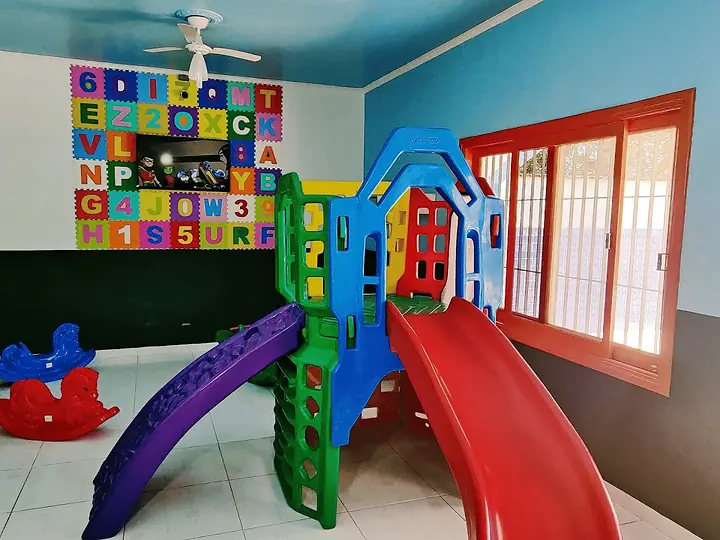 Brinquedoteca com escorregador colorido, cavalinho de balanço e parede de letras